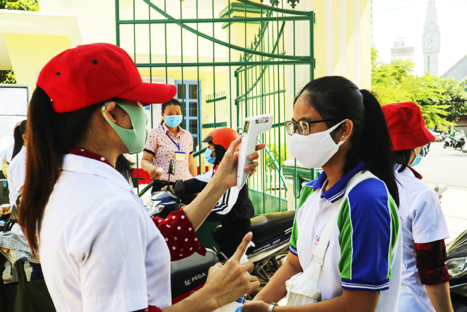 Cán bộ y tế đo thân nhiệt, kiểm tra sức khỏe cho học sinh trước khi vào thi tốt nghiệp. 