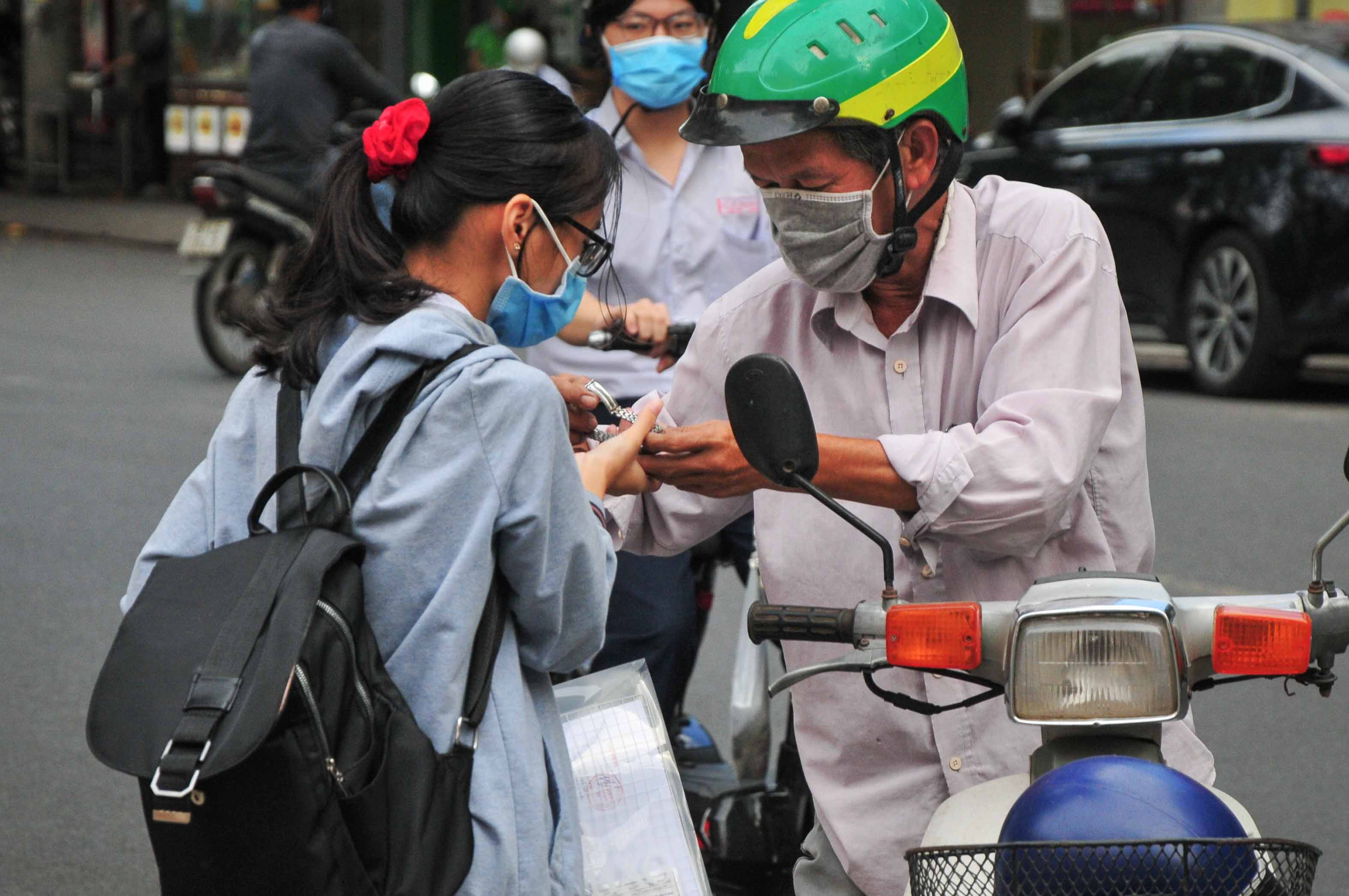 Tại điểm thi Trường THPT Lý Tự Trọng (TP. Nha Trang), một người nhà thí sinh đưa đồng hồ đeo tay cho con em mình để có thể theo dõi giờ làm bài