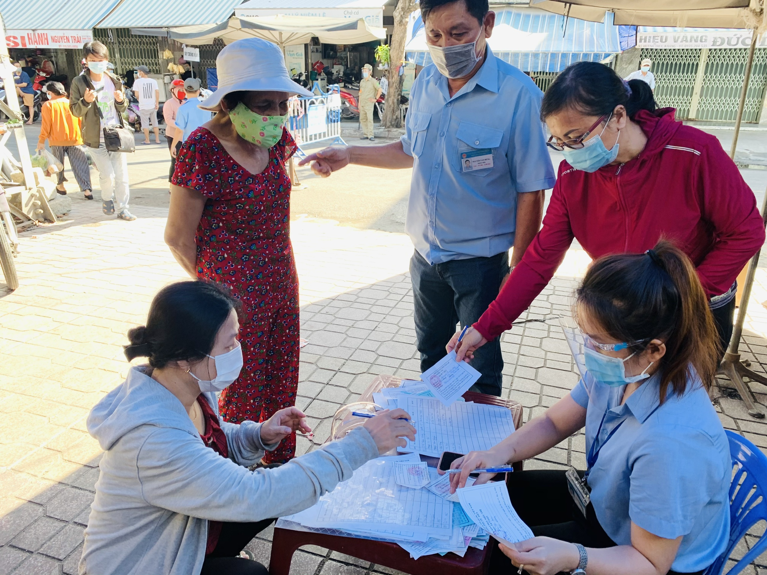 Chợ Xóm Mới cử nhân viên ghi chép lại tên của người đi chợ và thời gian đi chợ để có thể điều tra dịch tễ khi cần