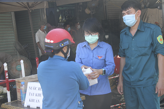 Cán bộ đoàn của phường Vạn Thạnh đến chợ Đầm để hỗ trợ việc tuyên truyền, hướng dẫn người dân đi chợ bằng phiếu, phụ giúp việc xịt nước rửa tay khử khuẩn cho khách đi chợ