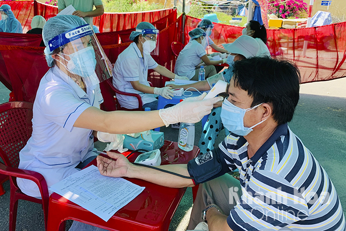 Một nhân viên y tế đang khám sức khỏe cho người đi tiêm.