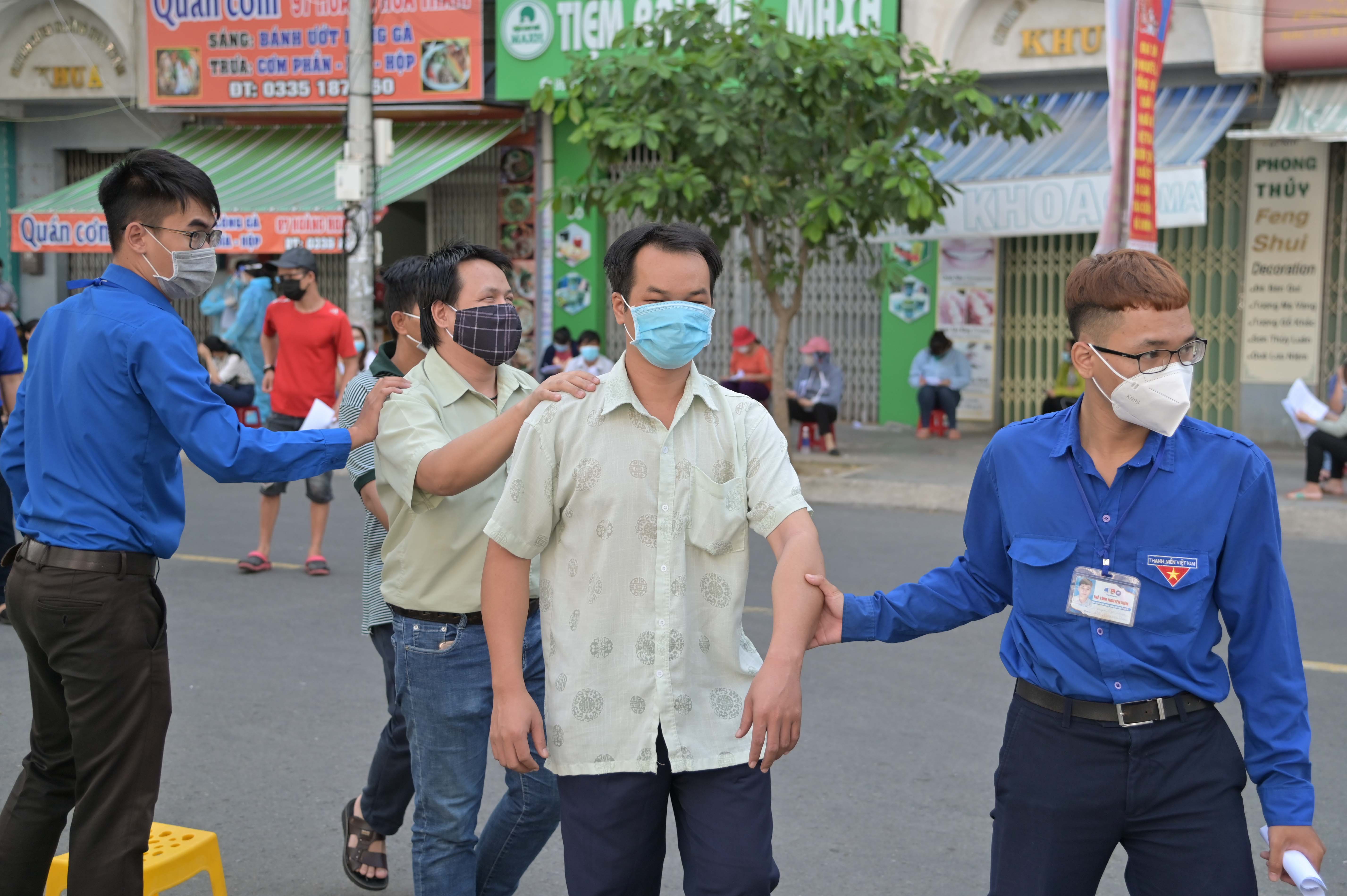 Tại điểm tiêm ở số 26 Hoàng Hoa Thám, các tình nguyện viên tham gia hỗ trợ người khiếm thị để làm thủ tục trước tiêm