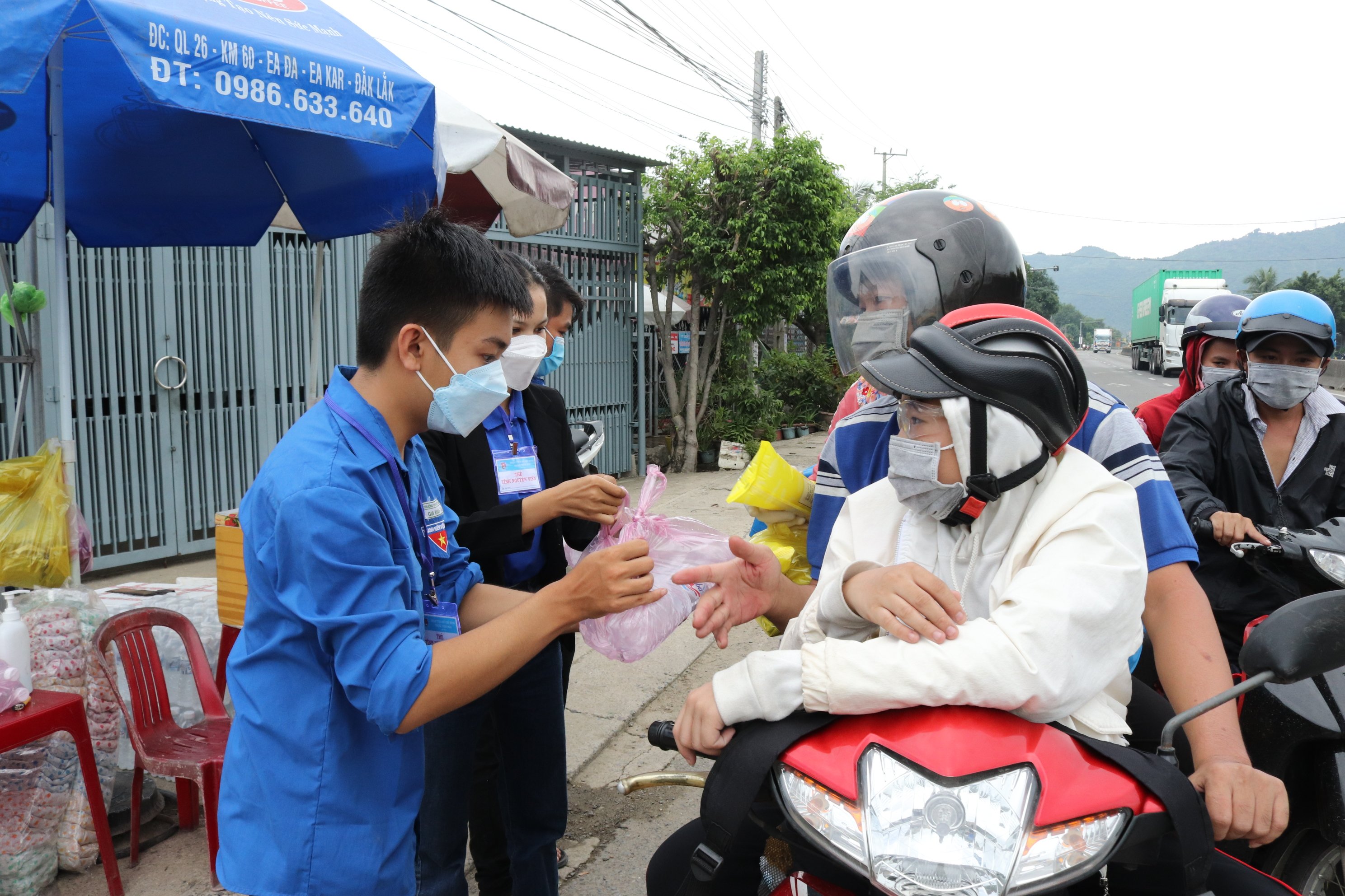 Thanh niên tình nguyện phát cơm, bánh ngọt...cho người lao động về quê.