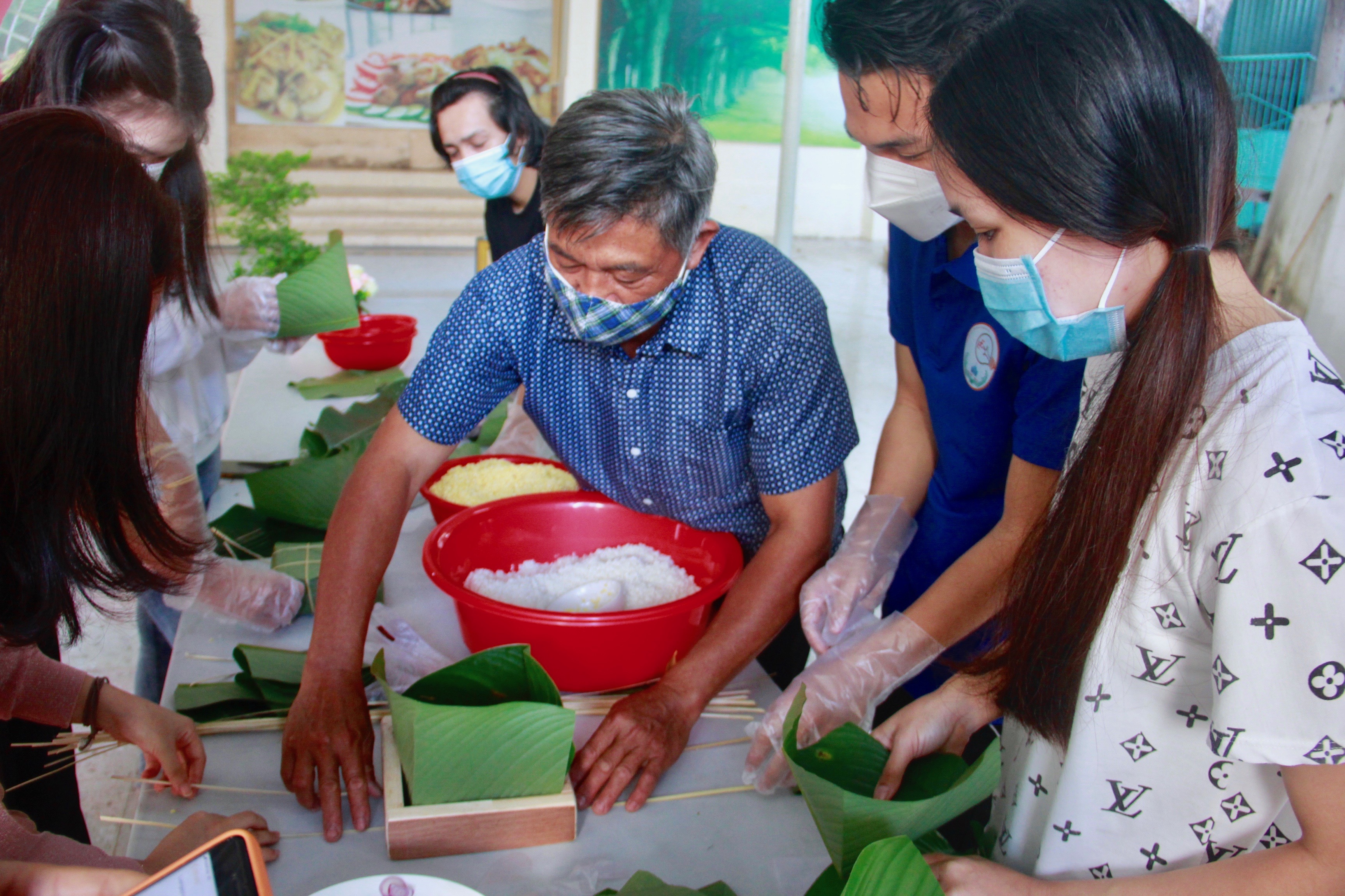 Sinh viên Lào sẽ được các nghệ nhân gói bánh chưng hướng dẫn gói. 