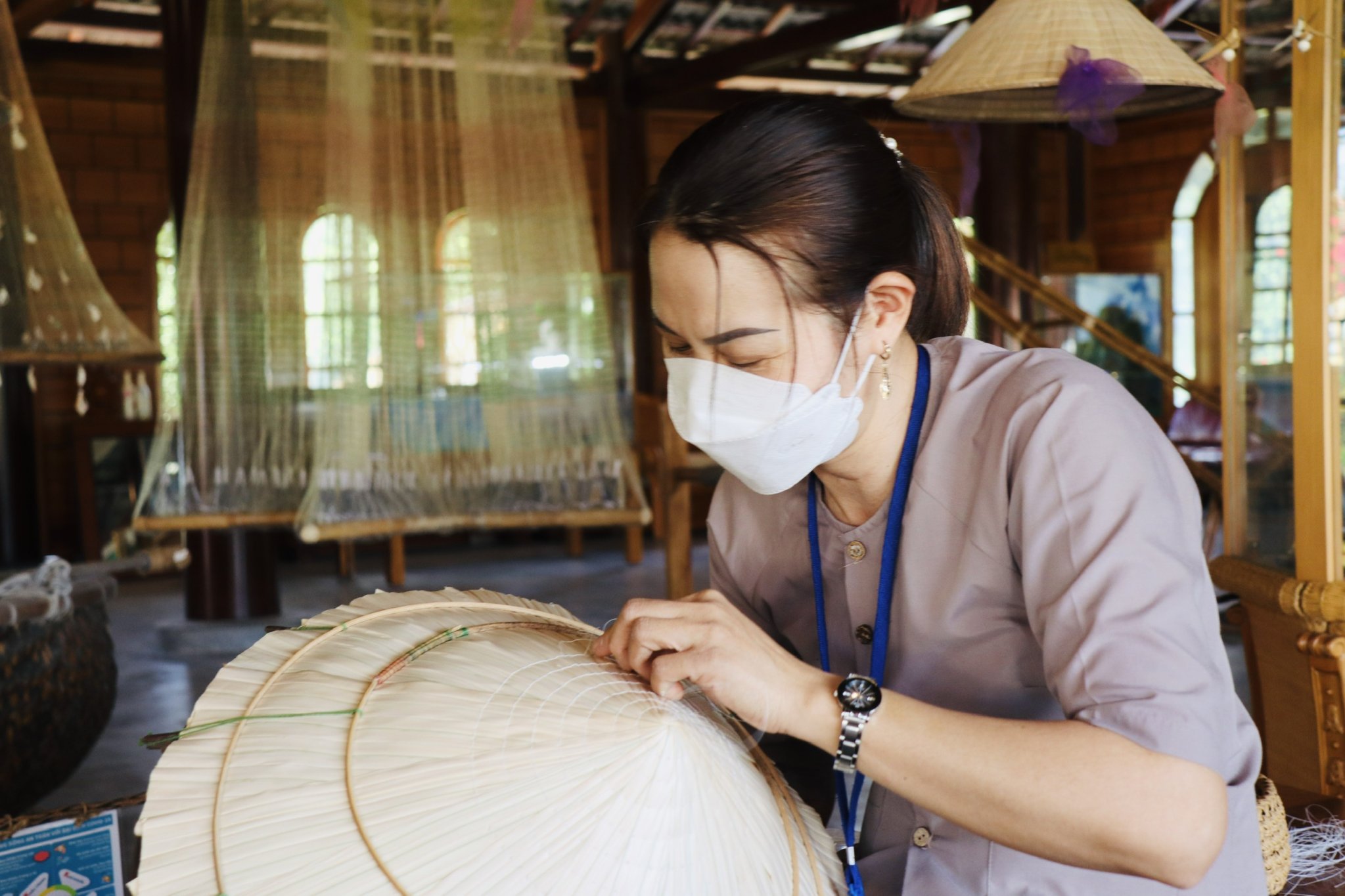 Nữ nhân viên làng nghề trình diễn nghề chằm nón lá