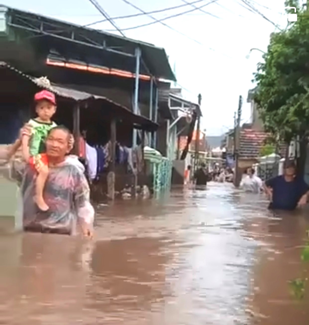 Người dân đưa trẻ em đi tránh trú khỏi khu vực ngập sâu do mưa lớn kết hợp với triều cường.