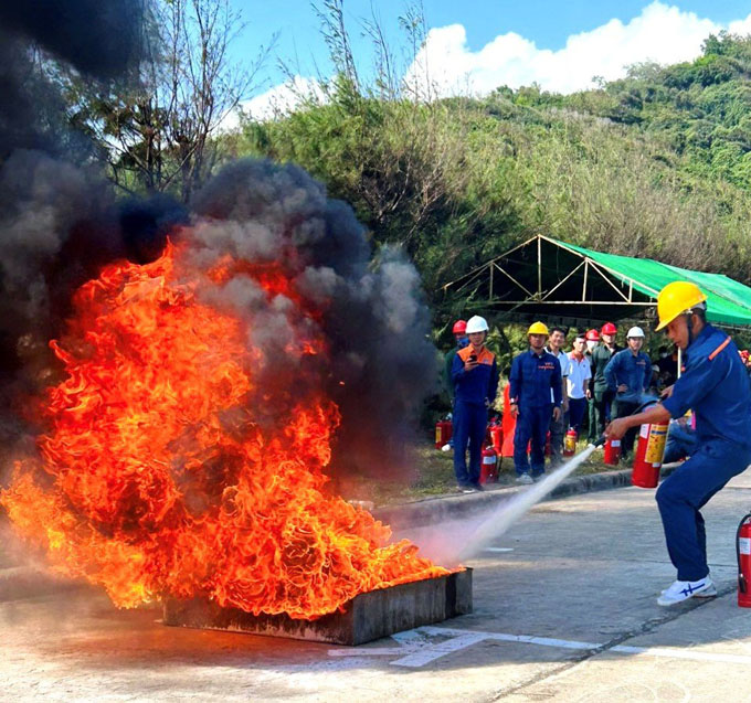 Thí sinh thực hiện phần thi dùng mền dập tắt đám cháy xăng dầu.